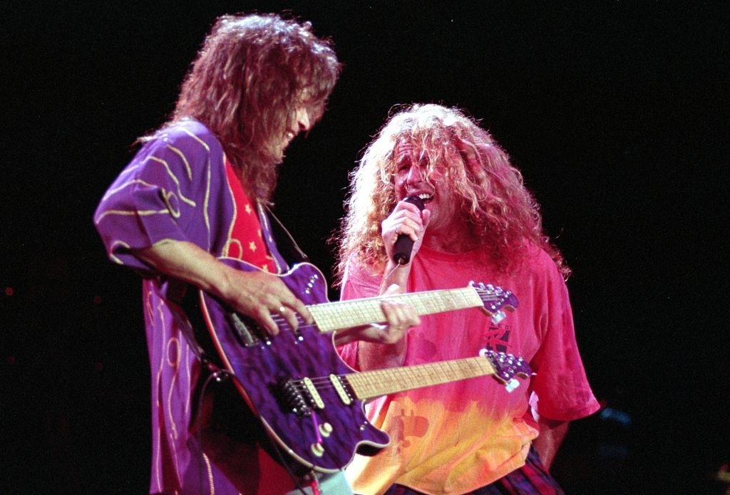 Eddie Van Halen plays a double-neck guitar while Sammy Hagar sings on stage during a live music performance