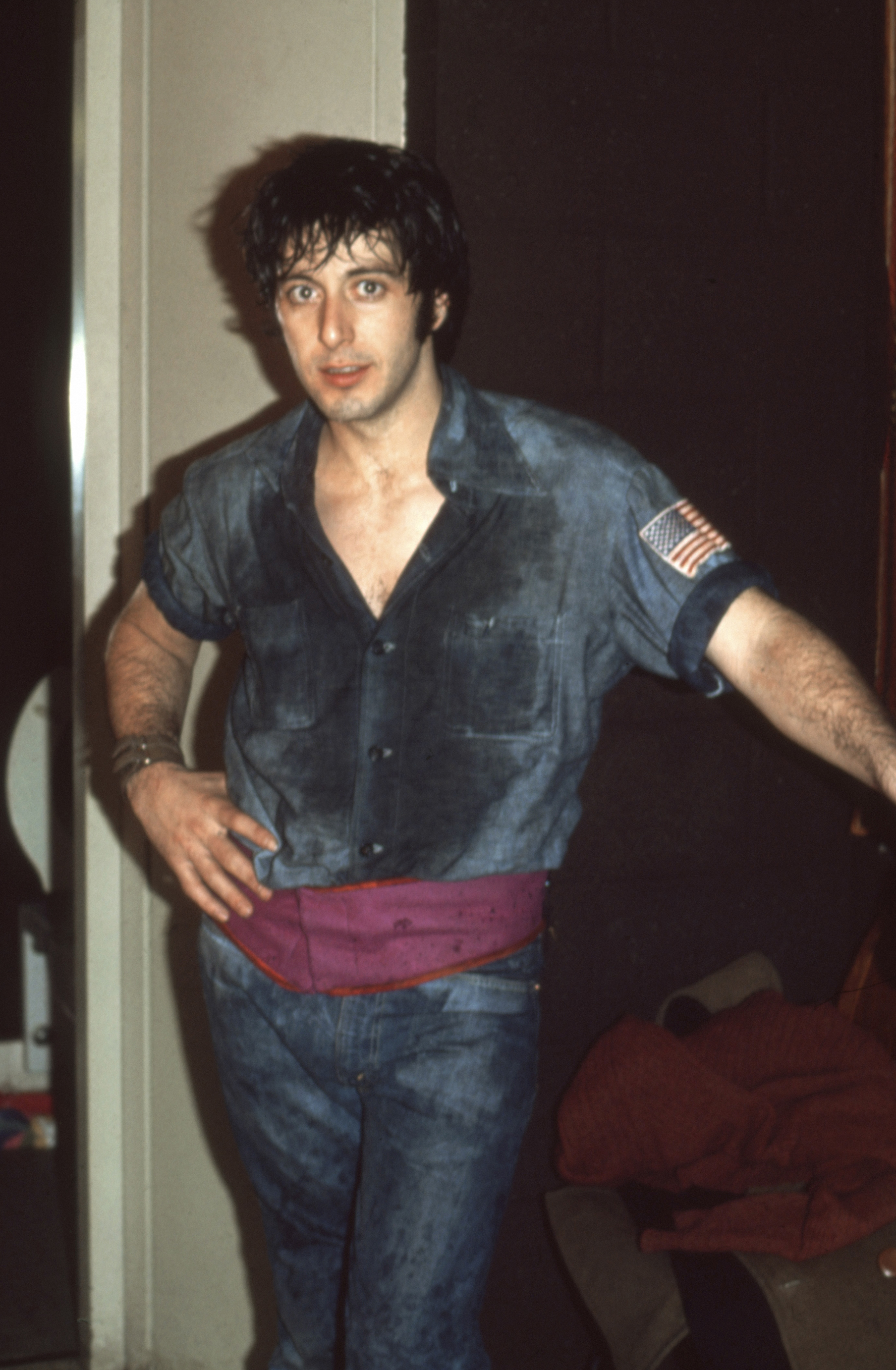 Al Pacino in a casual denim outfit with an American flag patch on the sleeve, posing indoors
