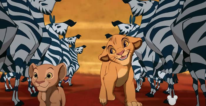 Animated lions Simba and Nala walk among zebras in a scene from Disney's The Lion King