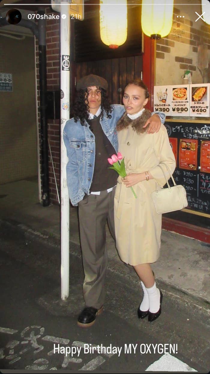 070Shake and Lily-Rose Depp standing together with one holding tulips; text under the image reads &quot;Happy Birthday MY OXYGEN!&quot;