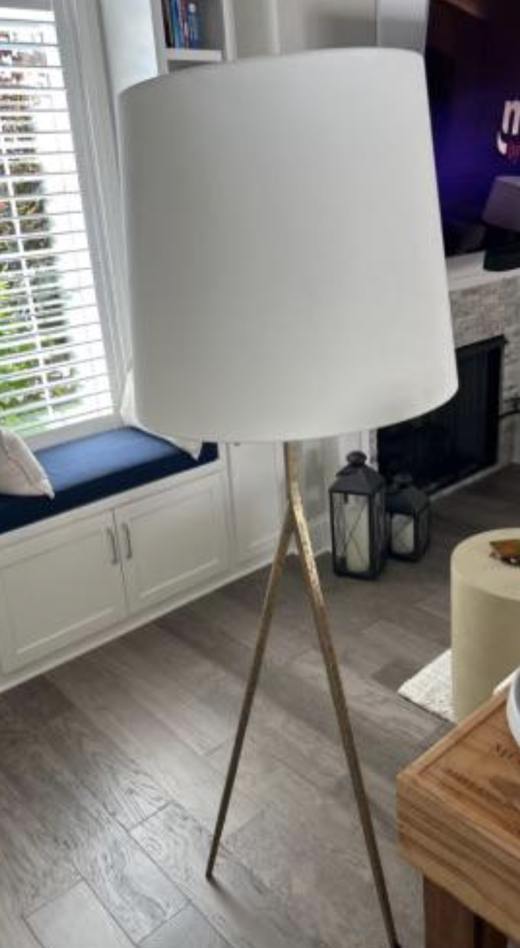 Modern living room with a tripod floor lamp, white shade, window seat with cushions, lantern decor, and a fireplace