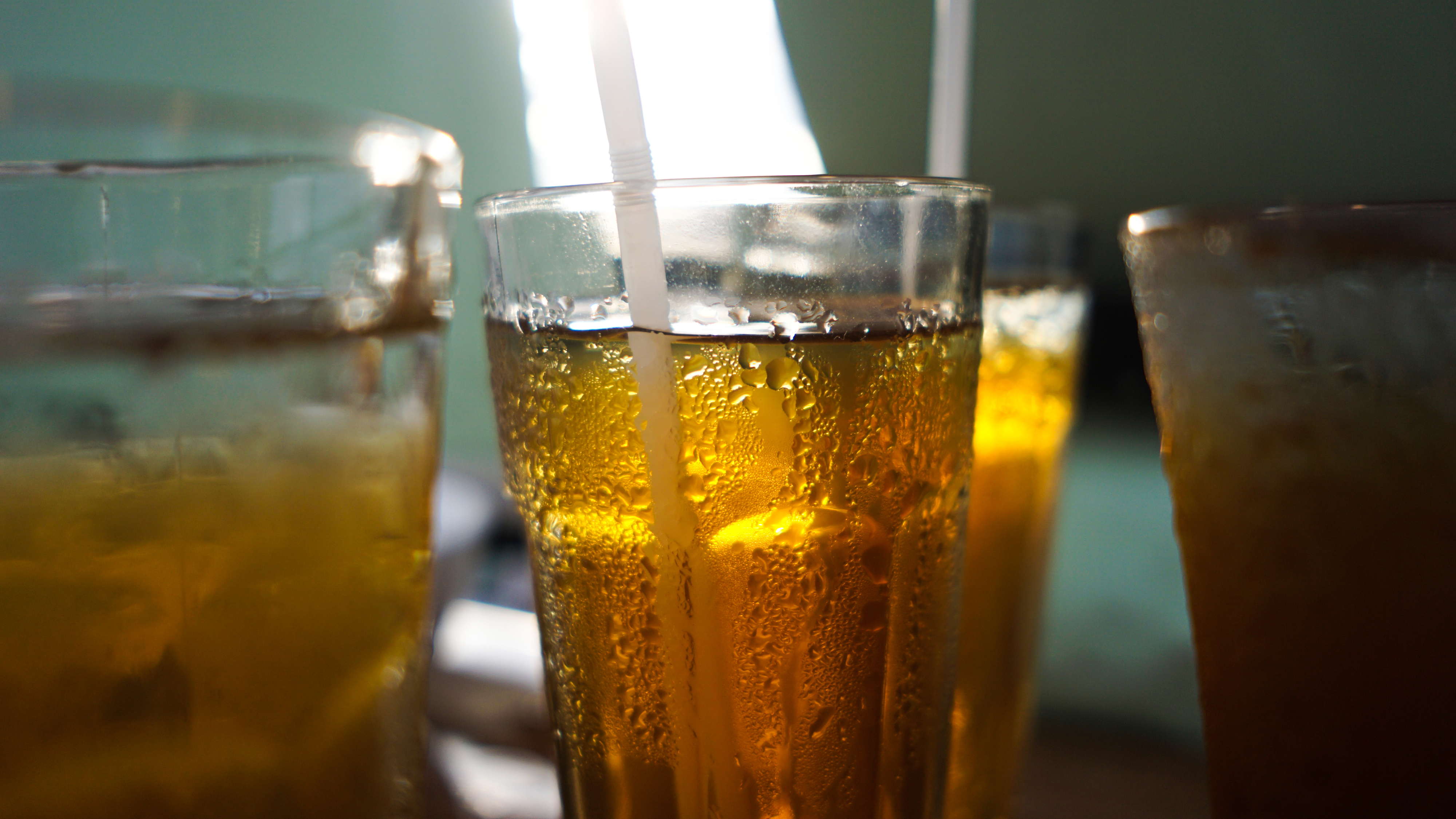 Close-up of several glasses filled with iced tea, each with a straw