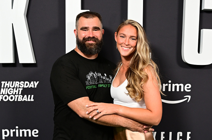 Jason Kelce, in casual attire, and Kylie Kelce, in a white top and beige skirt, pose together at a promotional event for the documentary "Kelce" on Prime