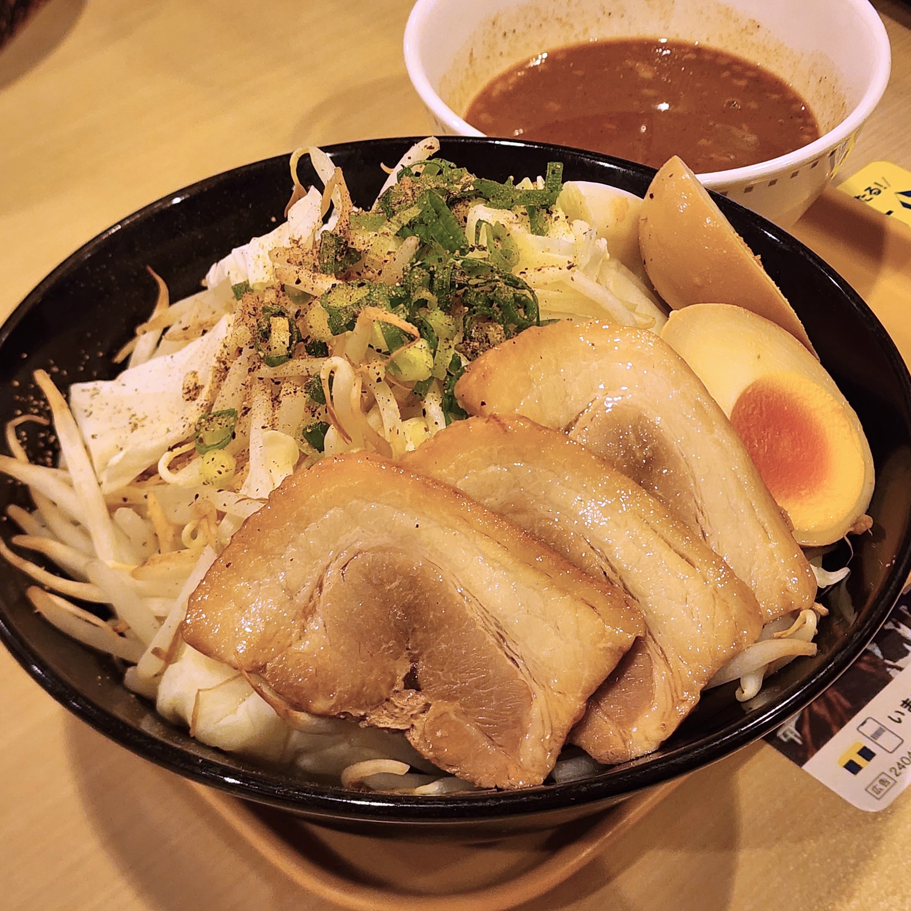 器に盛られたラーメンと豚肉のスライス、ゆで卵、もやし、ねぎ、そしてスープの入った別の器が横に配置されています。