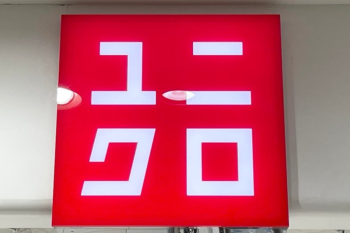 Uniqlo store sign with Japanese characters displayed on a red background within a white store interior