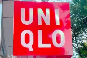 Uniqlo store sign hanging on a building with trees in the background