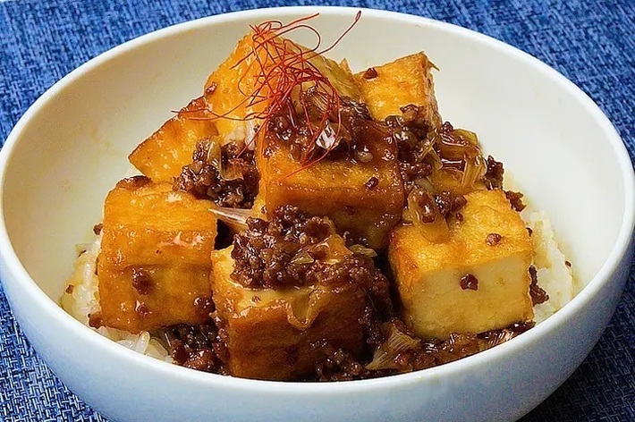 白いボウルに入った揚げ出し豆腐の料理が、おいしそうな照り焼きソースと一緒に盛り付けられています。