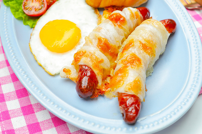 クロワッサン、焼きウィンナー、目玉焼き、レタス、プチトマトが盛られた青いプレート。