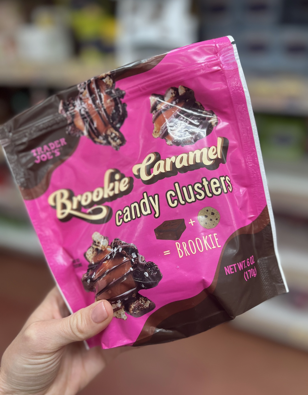 A hand holding a bag of Trader Joe's Brookie Caramel Candy Clusters