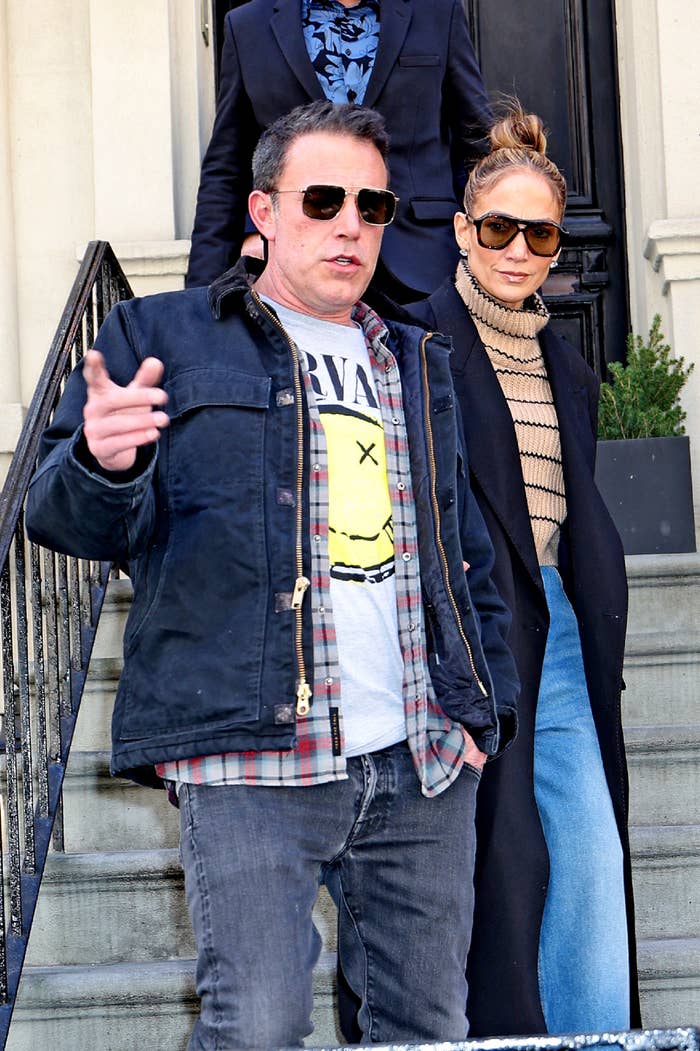 Ben Affleck in casual attire and Jennifer Lopez in a high-neck sweater and sunglasses, walking down the steps of a building