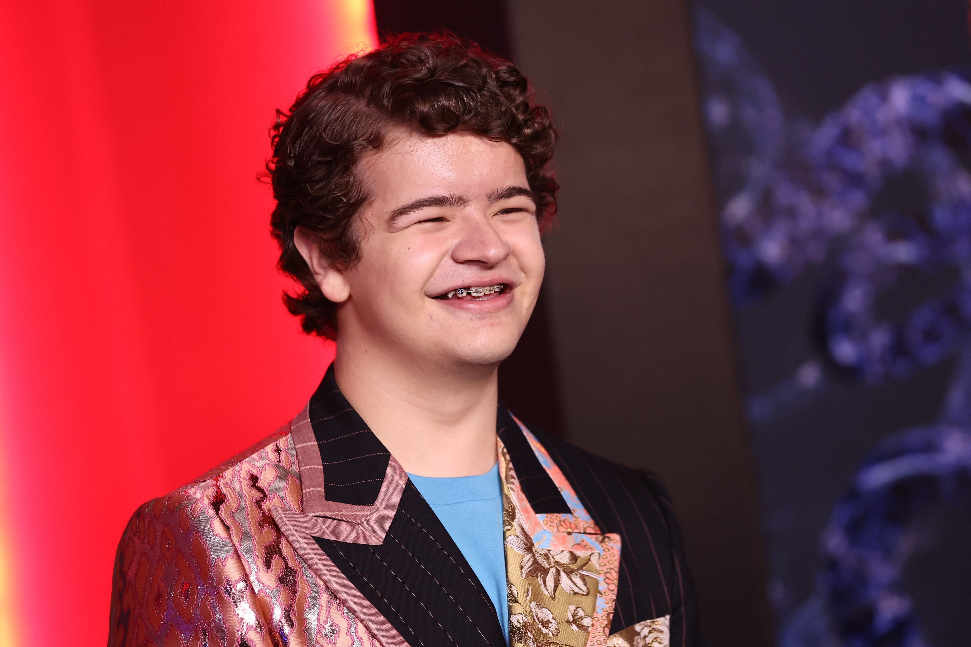 Gaten Matarazzo smiles while wearing a patterned blazer on the red carpet