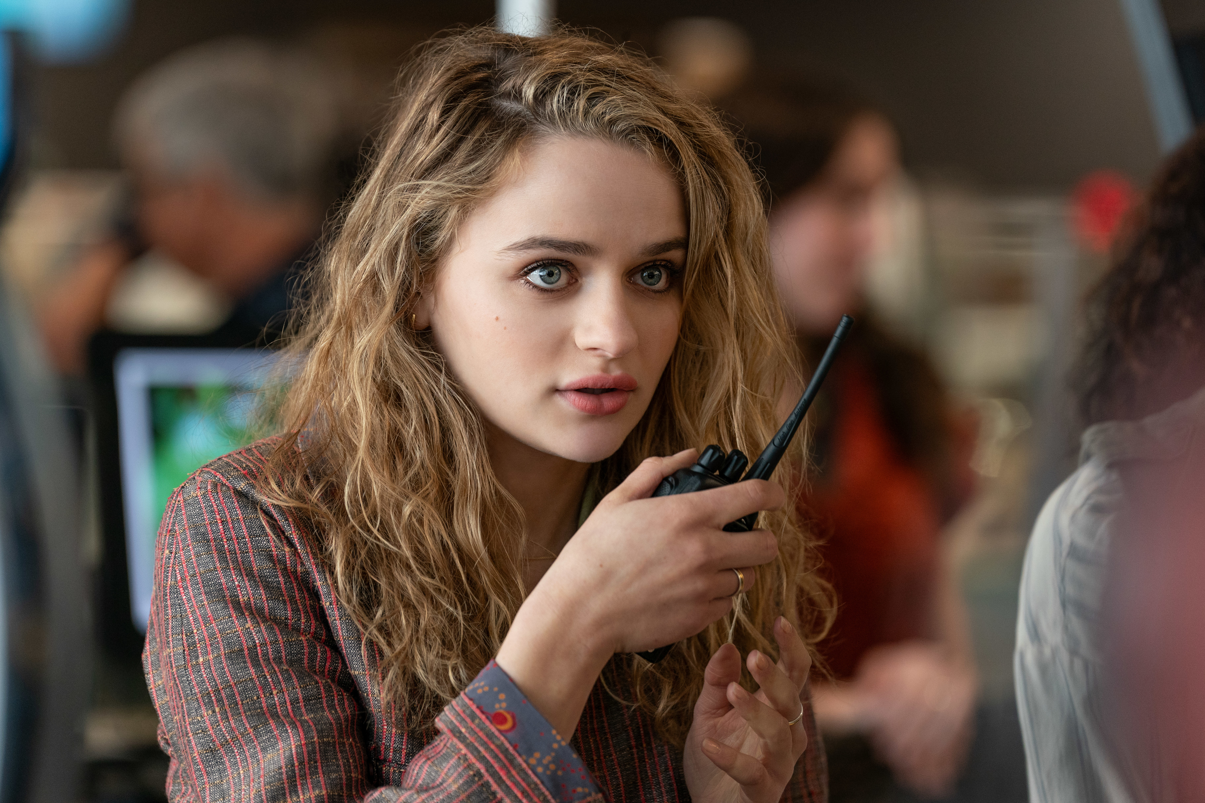 Joey King, with curly hair, holds a walkie-talkie and appears focused in a scene from the film