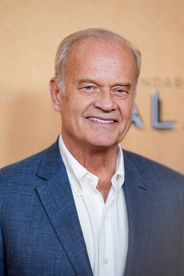 Kelsey Grammer smiling, dressed in a blazer and shirt, posing at an event