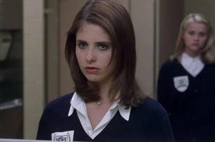 Sarah Michelle Gellar and Reese Witherspoon in school uniforms, looking serious in a hallway scene