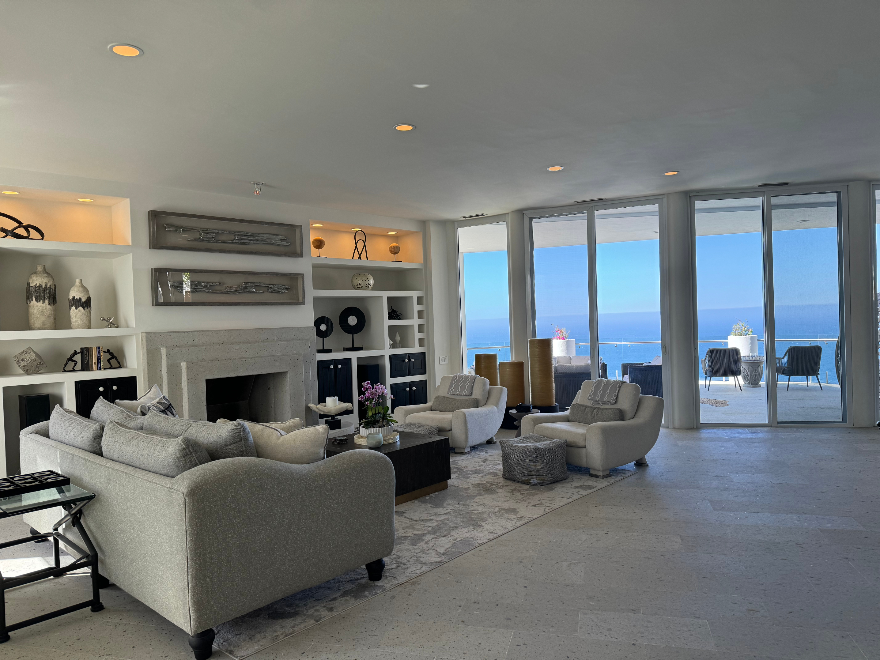 Spacious modern living room with large windows showcasing an ocean view, comfortable seating, and stylish decor