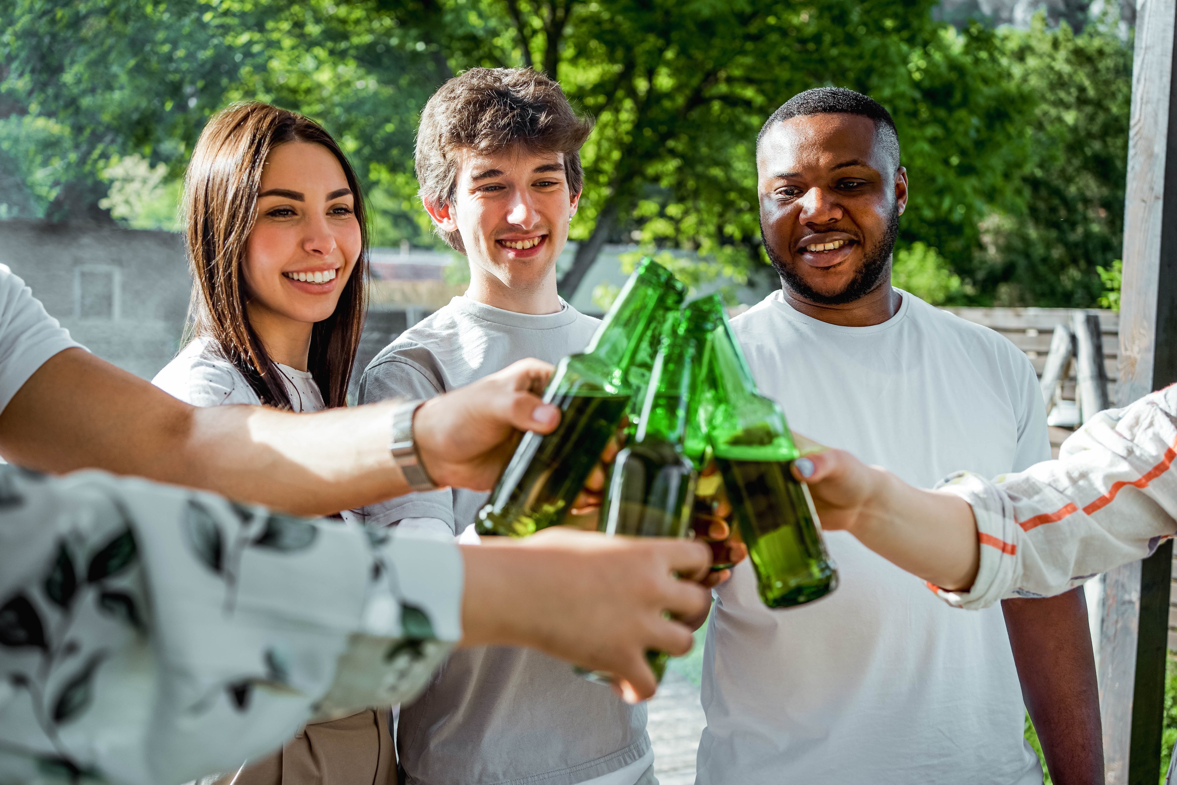 Group of friends toasting with beer bottles outside