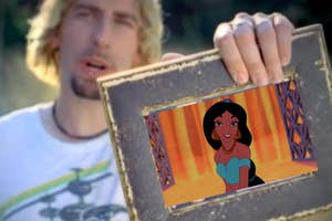 A man holds a wooden frame displaying a picture of Princess Jasmine from Disney's Aladdin smiling, wearing her signature outfit