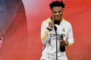 YouTube personality IShowSpeed on stage wearing a Real Madrid soccer jersey, holding a microphone in one hand and making a fist with the other