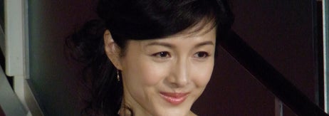 日本人女性がシンプルでエレガントなノースリーブのドレスを着て、笑顔を見せています。