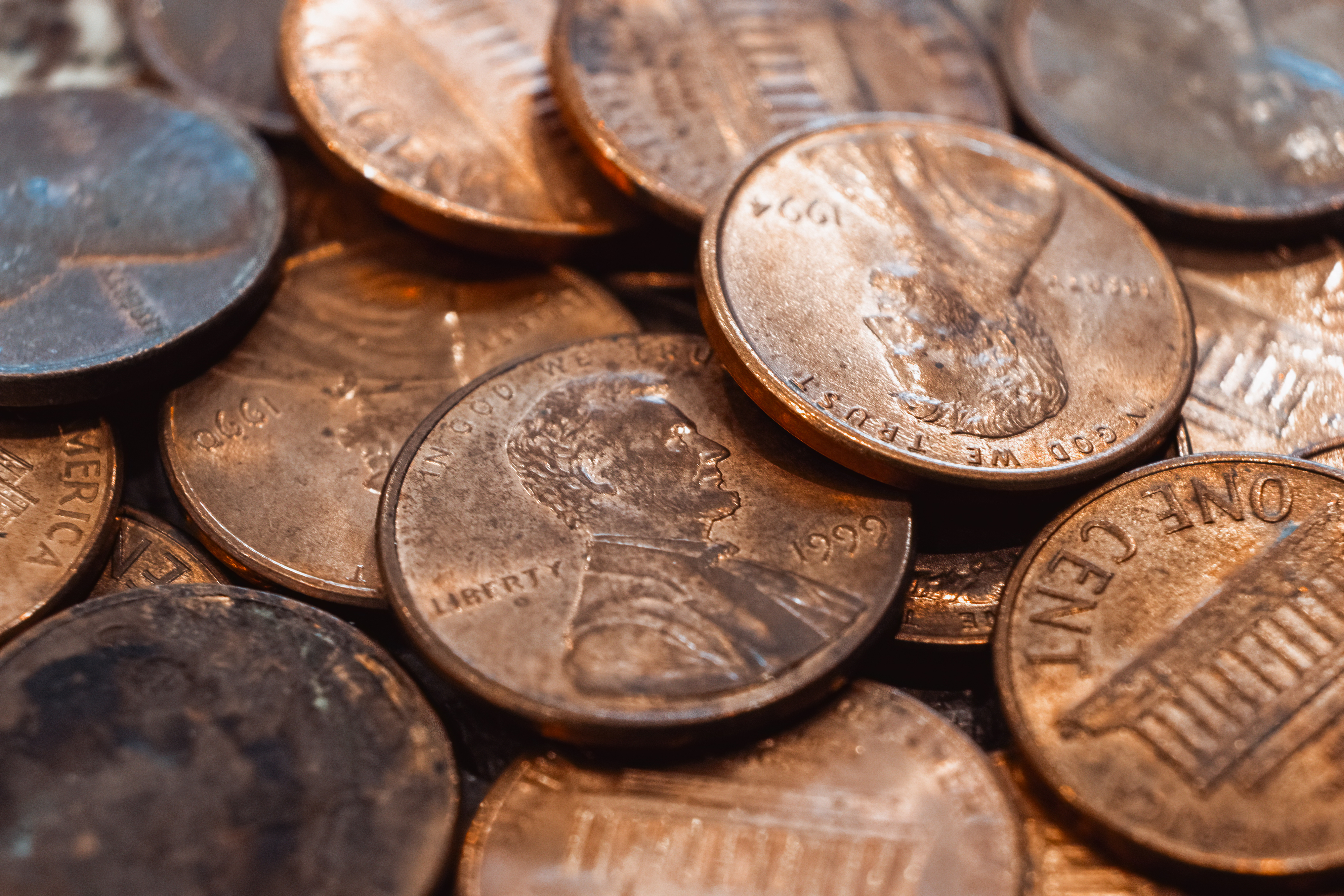 A pile of scattered US pennies, showcasing both heads and tails sides with different years visible