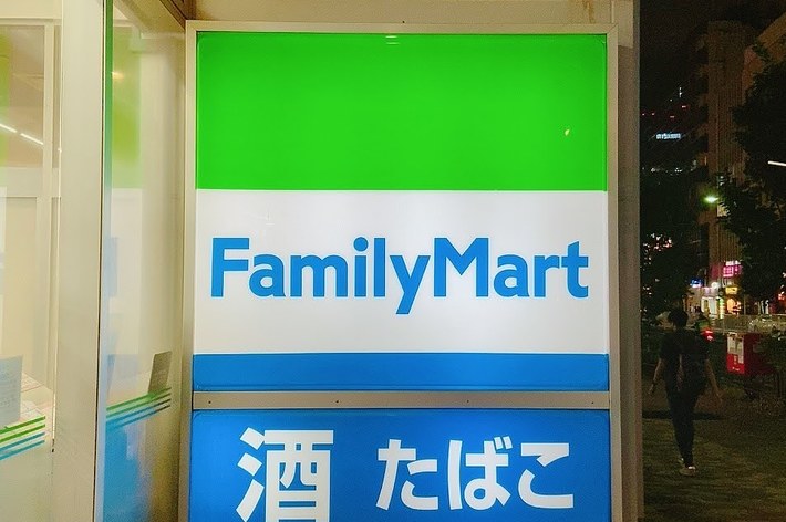 ファミリーマートの看板、上部は緑、下部は青、夜の街並み。