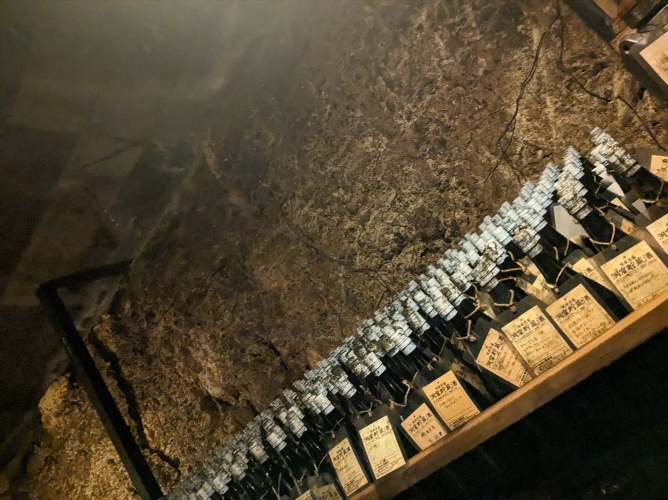 暗い部屋に整然と並べられた多数の酒瓶がある。