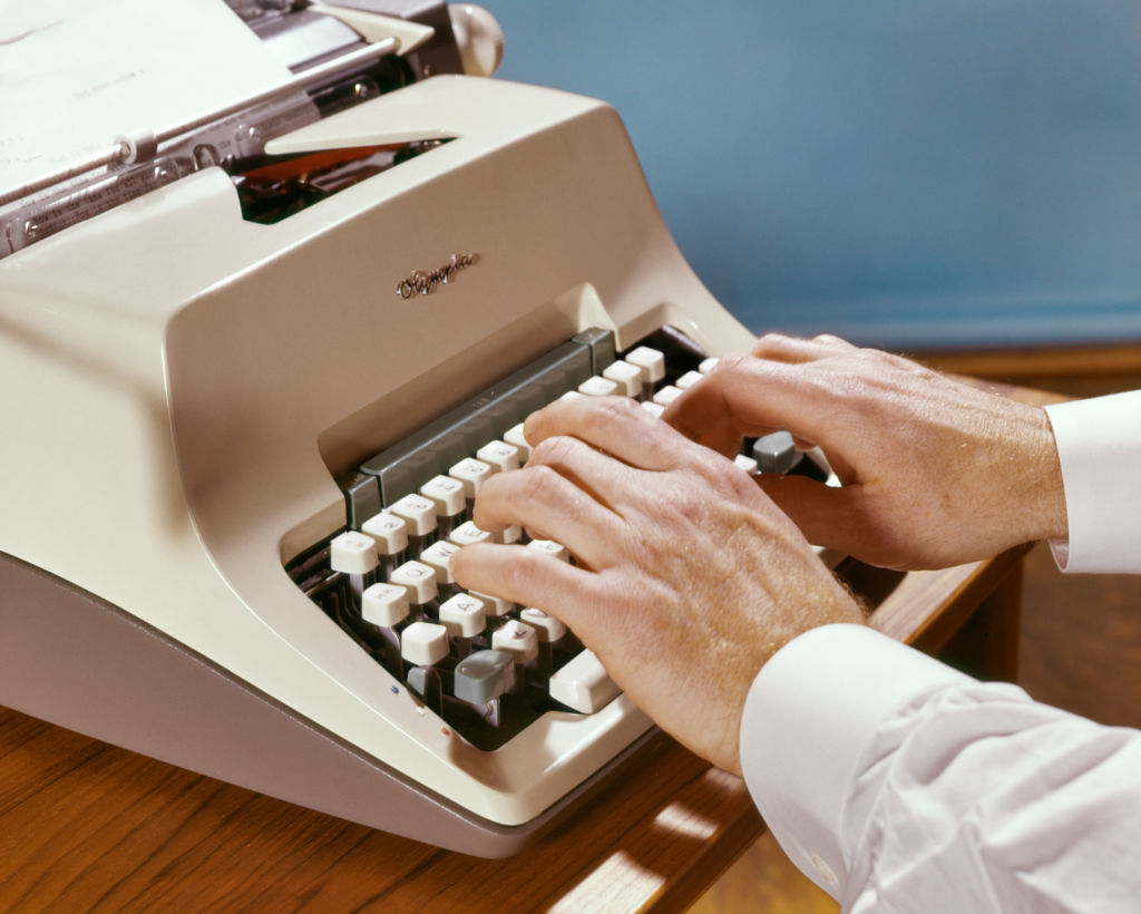 Person typing on a vintage typewriter, hands visible