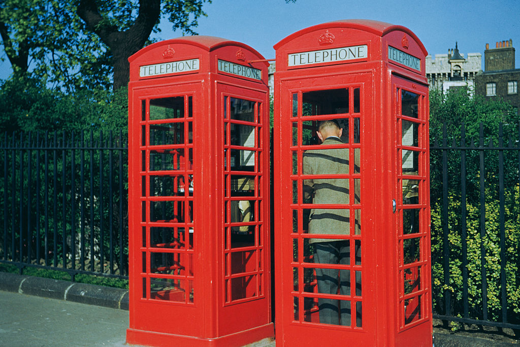 Two traditional British red telephone booths with a person visible in one booth