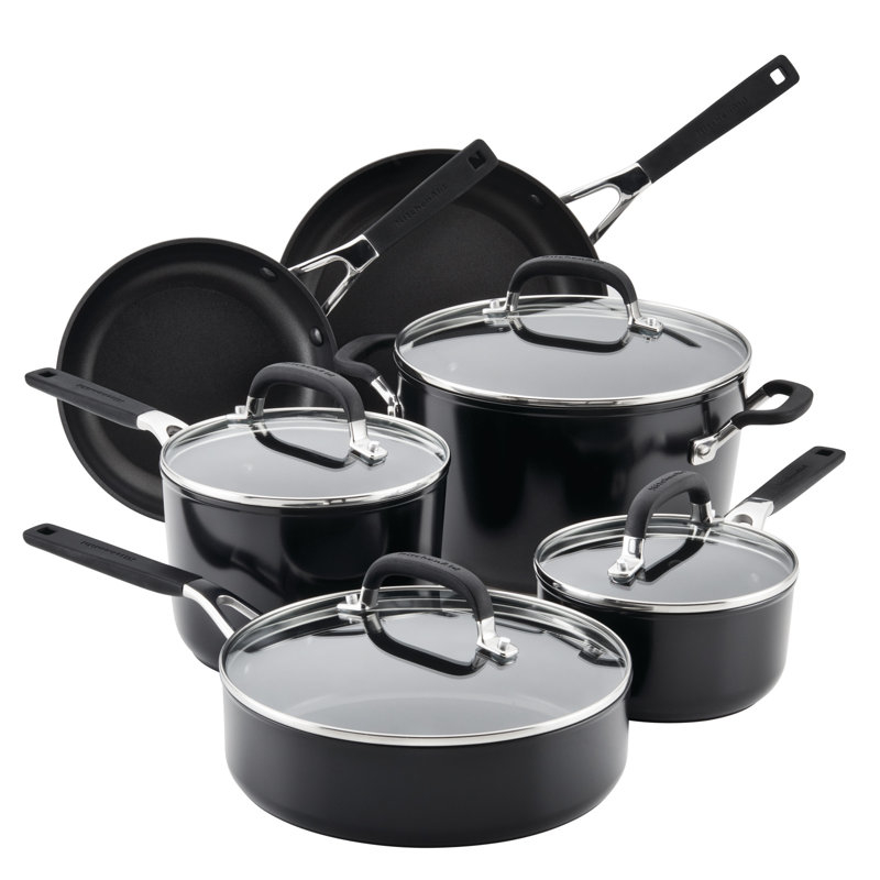A set of five black kitchen pots and pans with lids and silver handles