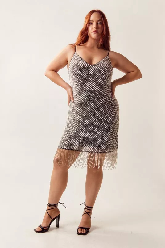 Woman in fringe dress and strappy heels poses confidently, showcasing outfit for shopping feature