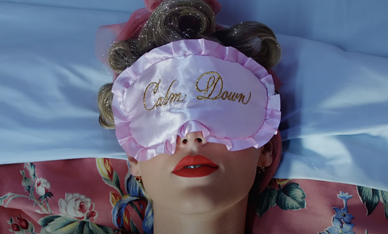 Person wearing a sleep mask with &#x27;Calm Down&#x27; text, lying down with eyes closed