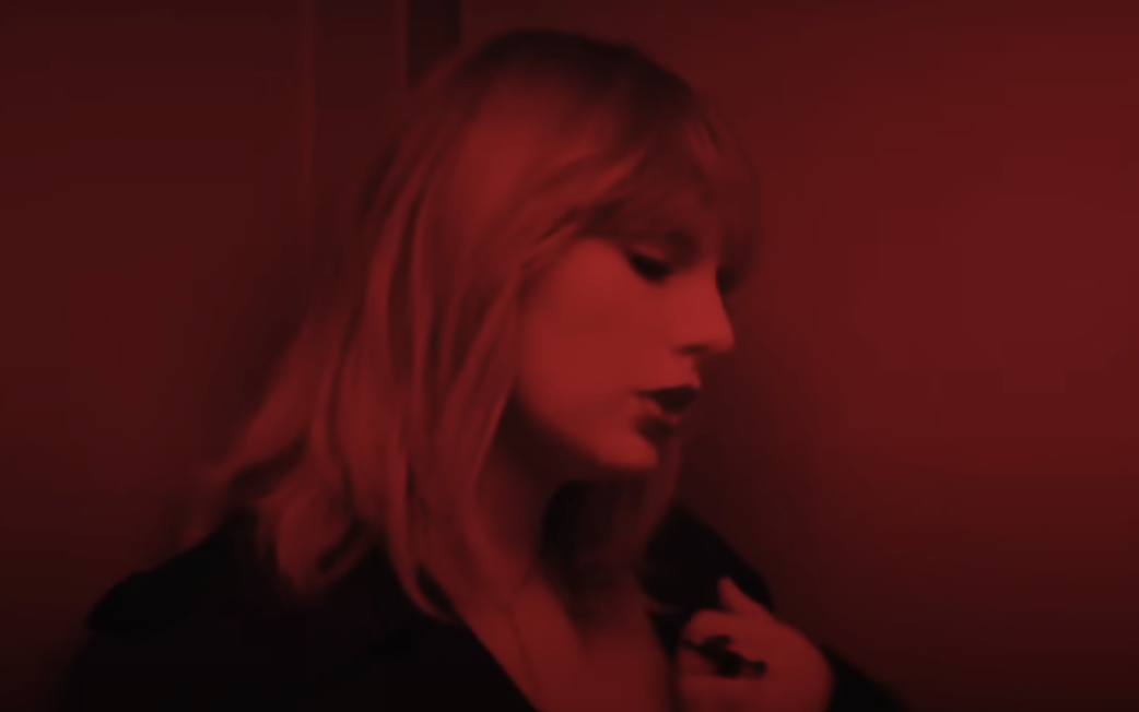Close-up of a person with a fringe, in a dimly lit red room