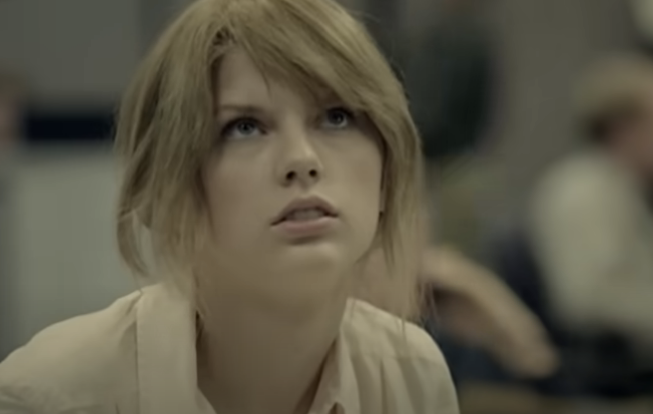 Woman with short hair looking upwards, seemingly in thought, indoors
