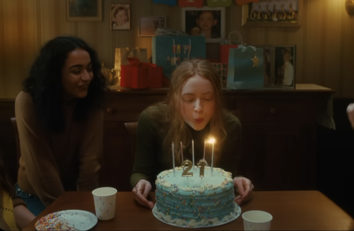 A girl blows out candles on a birthday cake with a friend watching