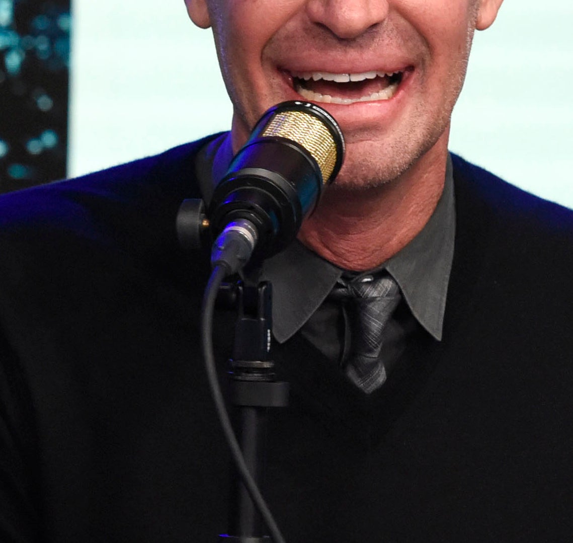 Jeff Lewis seated at a table speaking into a microphone, surrounded by Christmas-themed decorations