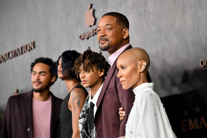 Will Smith and family posing together; Smith in a suit, family in varied stylish attire