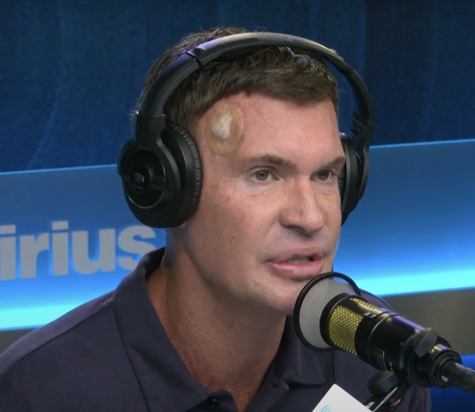Jeff with a microphone headset in a radio studio, focusing intently