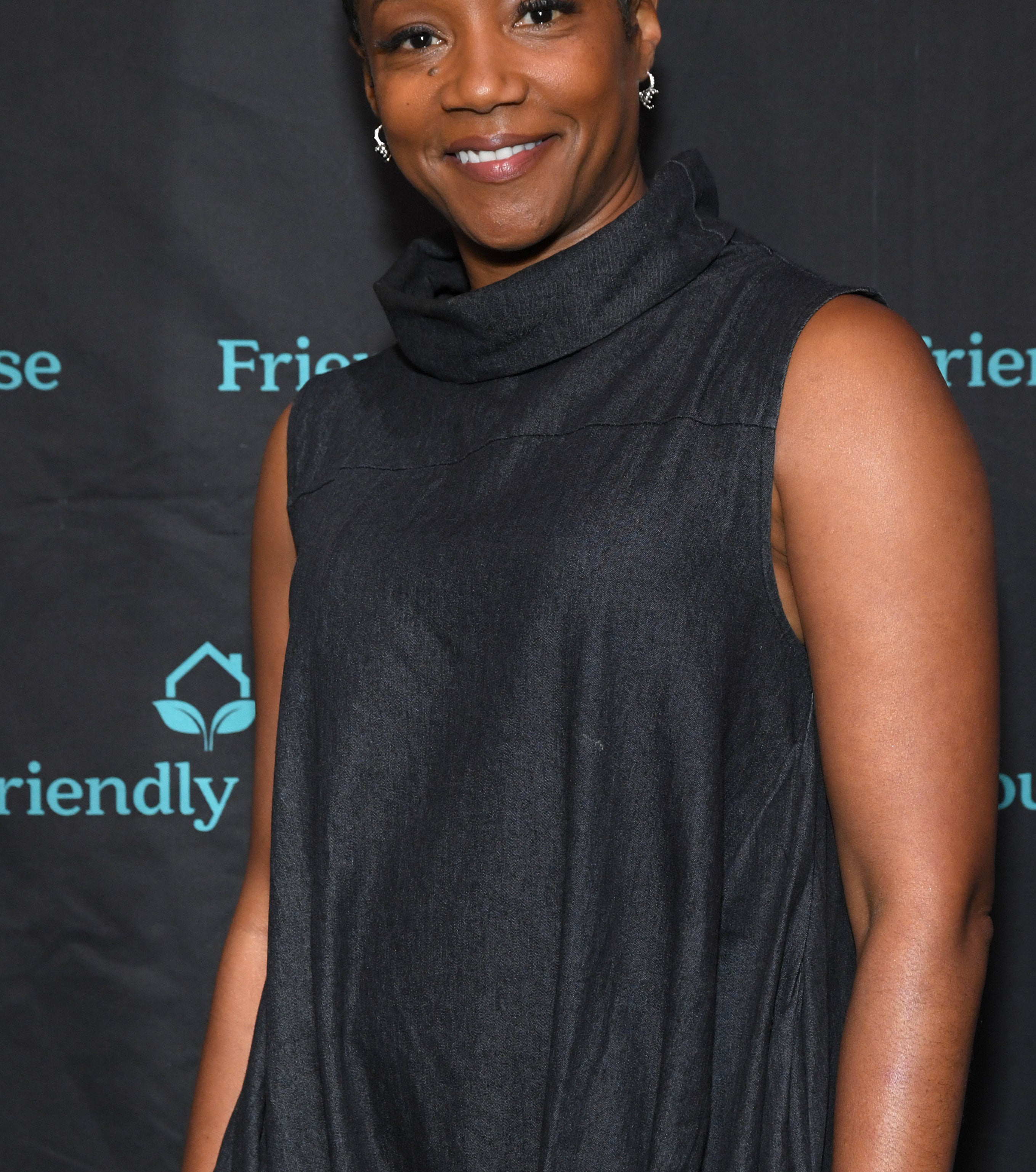 Tiffany Haddish in a black sleeveless cowl neck dress at a Friendly House event