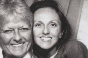 Two women smiling closely together in a black and white photo booth picture