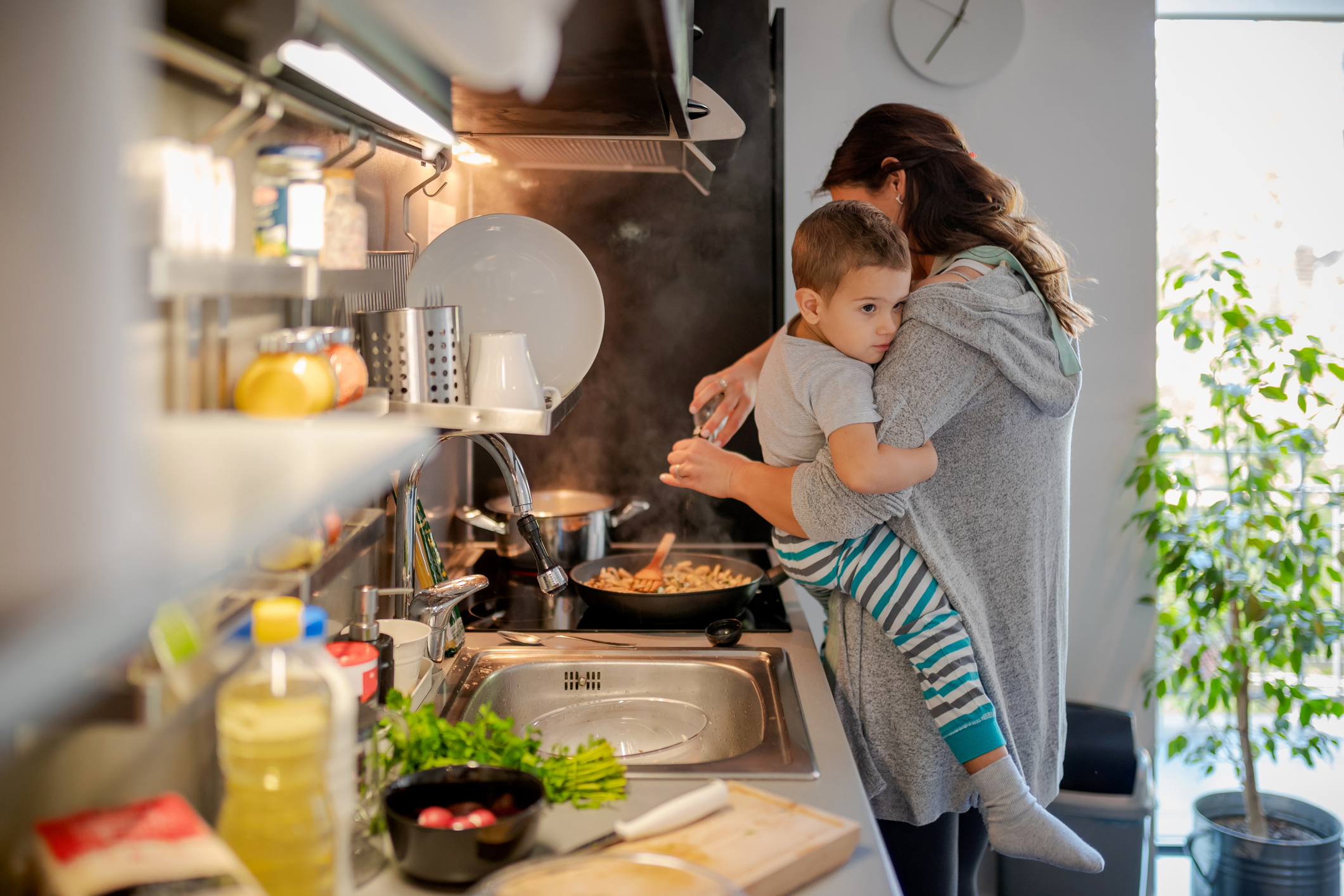 Person cooking while holding a young child in a home kitchen