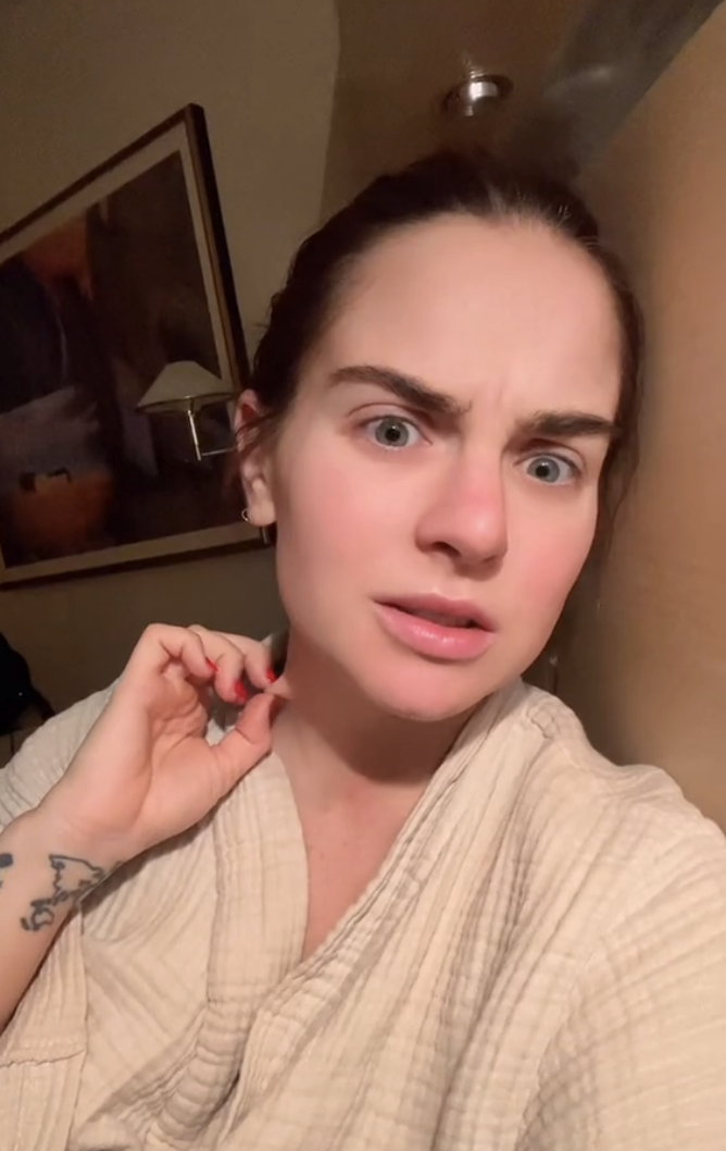 JoJo in a bathrobe looking surprised, with a tattoo on her left arm