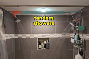 Two showerheads on opposite walls in a tiled shower with shelves of bath products