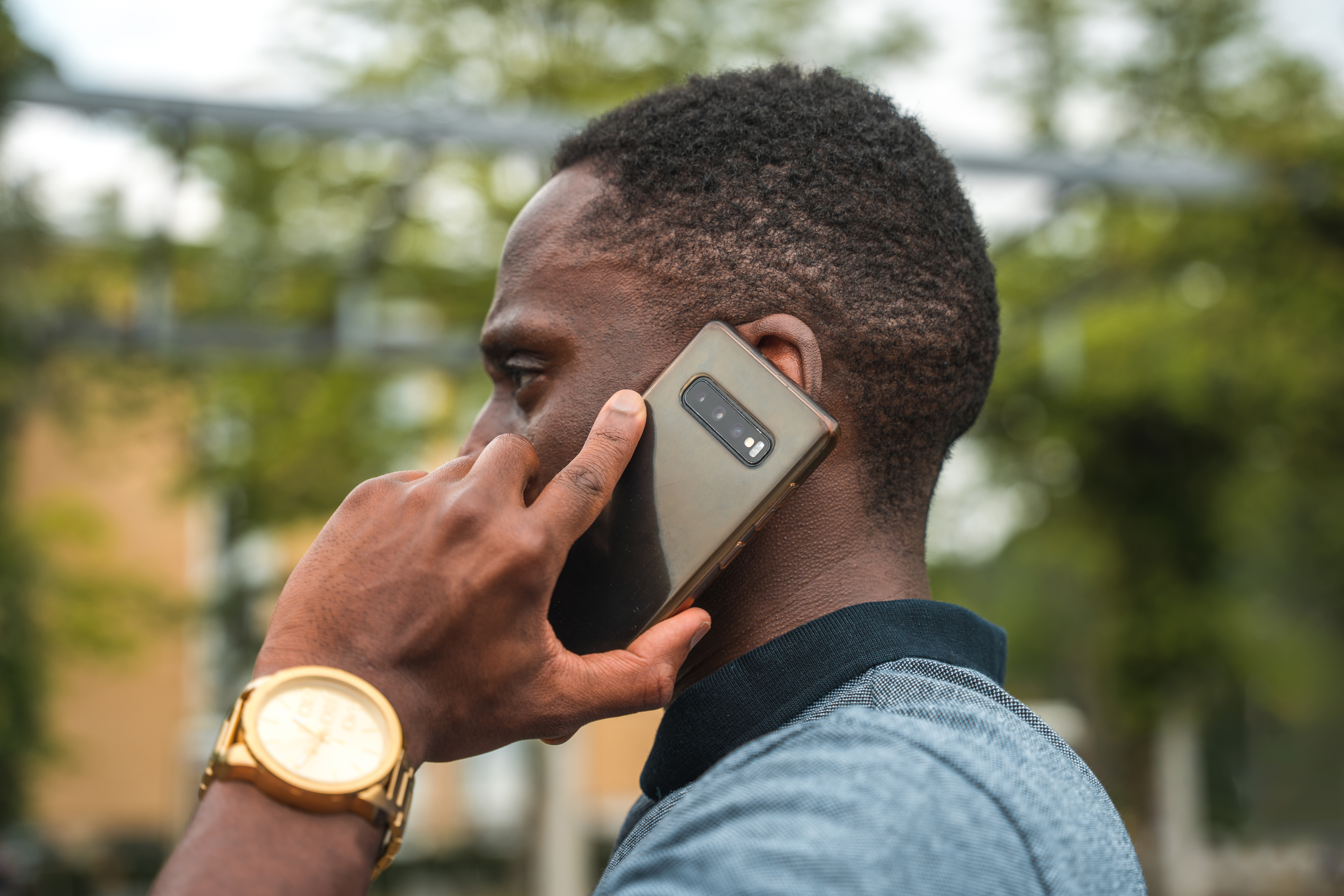 Person on a call using a smartphone, wearing a watch, focus on the hand and phone