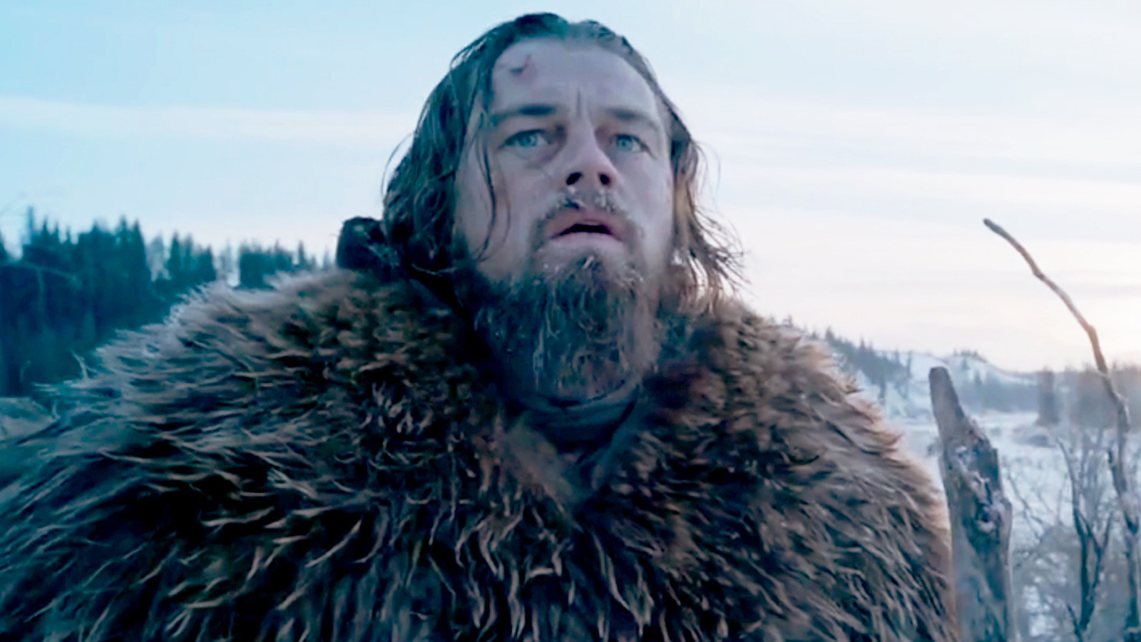 Leonardo DiCaprio in character, wearing a fur coat, looks determined in a snowy landscape