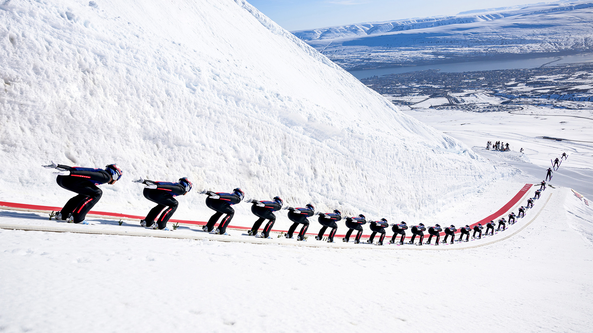 A line of skiers in a synchronized pose descending a snowy slope