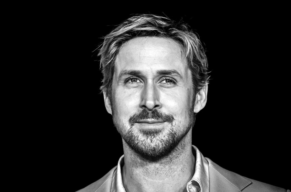 Black and white portrait of Ryan Gosling with a light beard, wearing a shirt and jacket