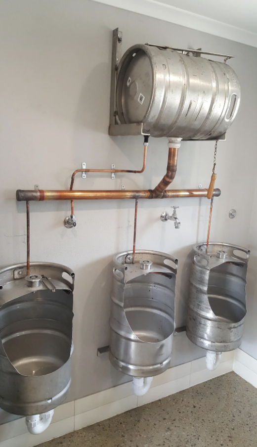 A creative bathroom setup with beer kegs repurposed as urinals