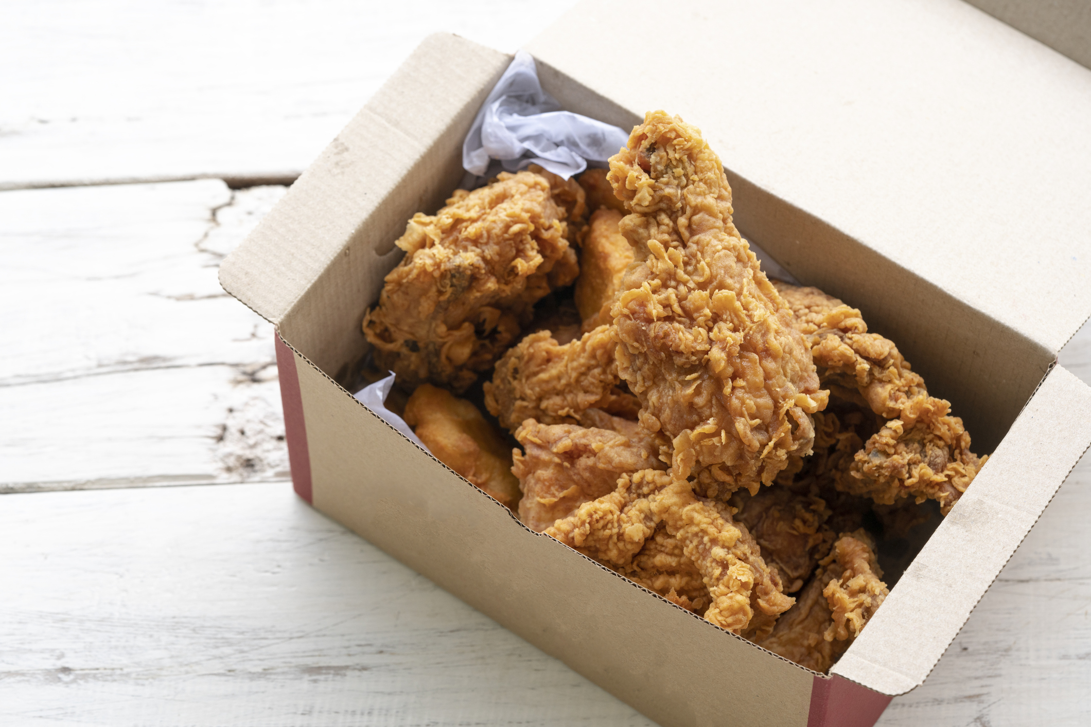 Open takeout box filled with pieces of fried chicken on a table, relevant for discussions on family meals or fast food options