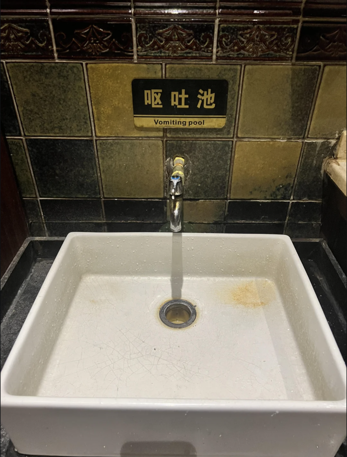A sink with a sign above labeled &quot;Vomiting pool&quot; in English and Chinese
