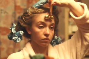 Woman using a jade roller on her face, hair in curlers, focused expression